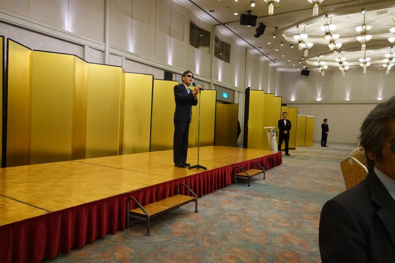 金屏風の前で司会者が